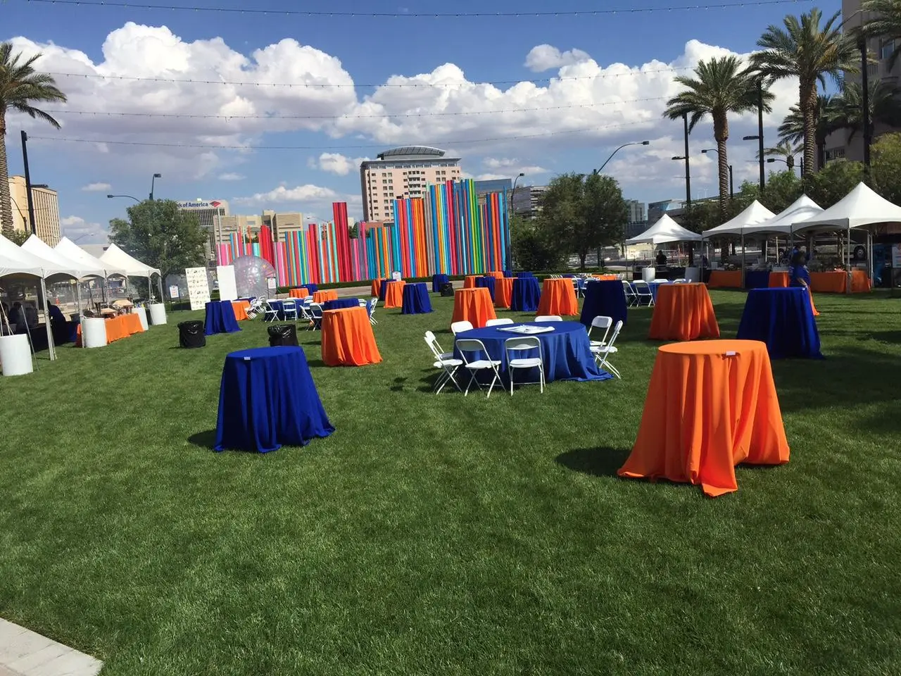 Outdoor company picnic with blue and orange tables, tents, and art installation in Las Vegas